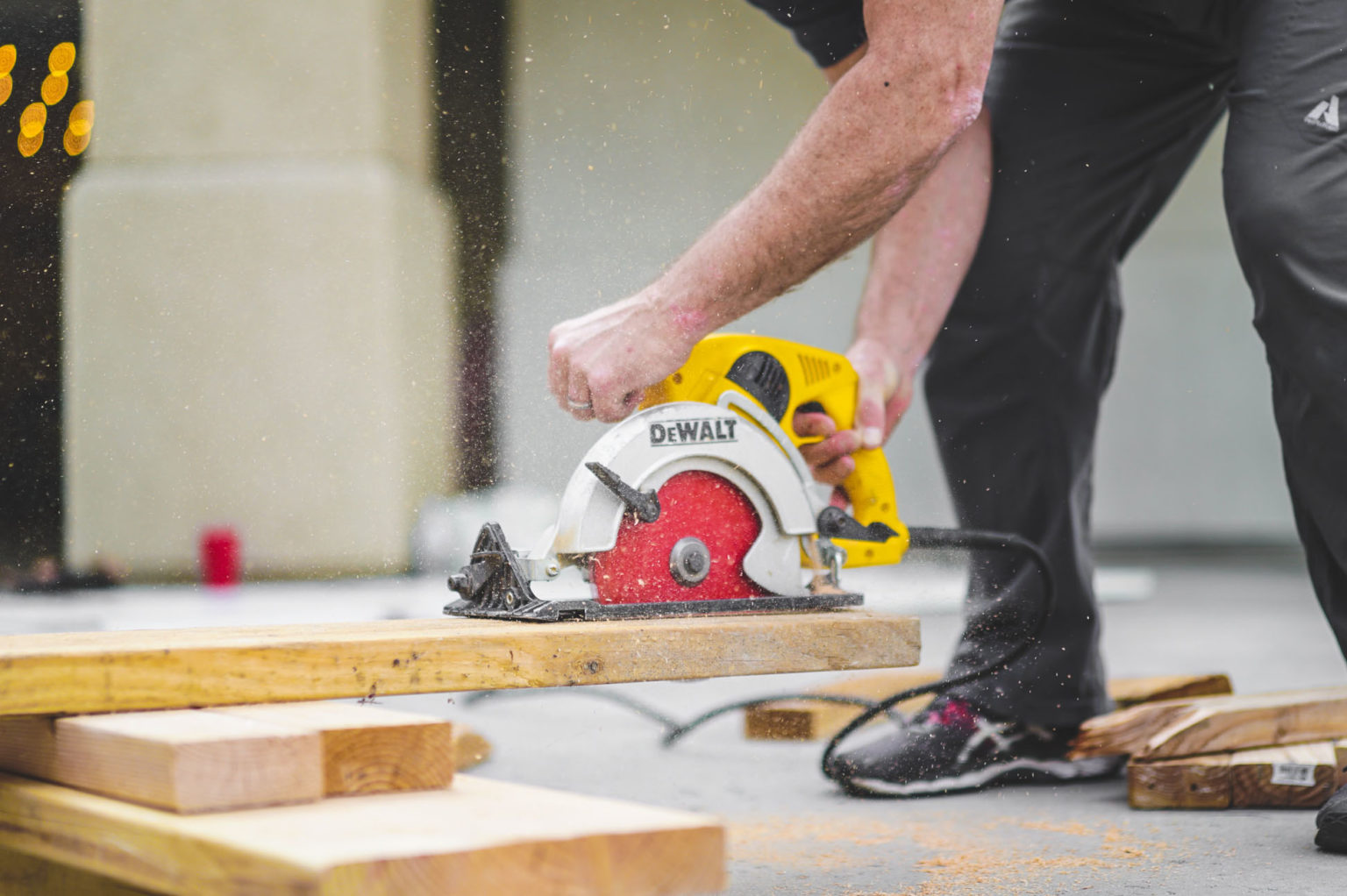 Builder cutting wooden plank indoors with a hand-held circular saw